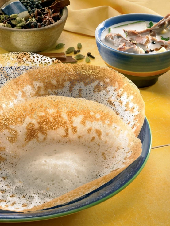 a plate topped with soup next to bowl filled with food