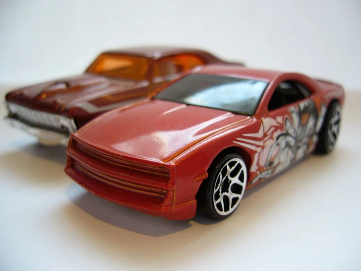 two red toy cars sitting side by side on top of a table