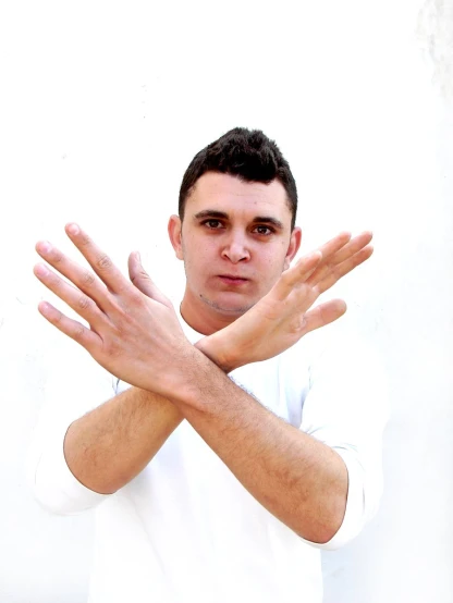 a man with his hands out and wearing a white t - shirt