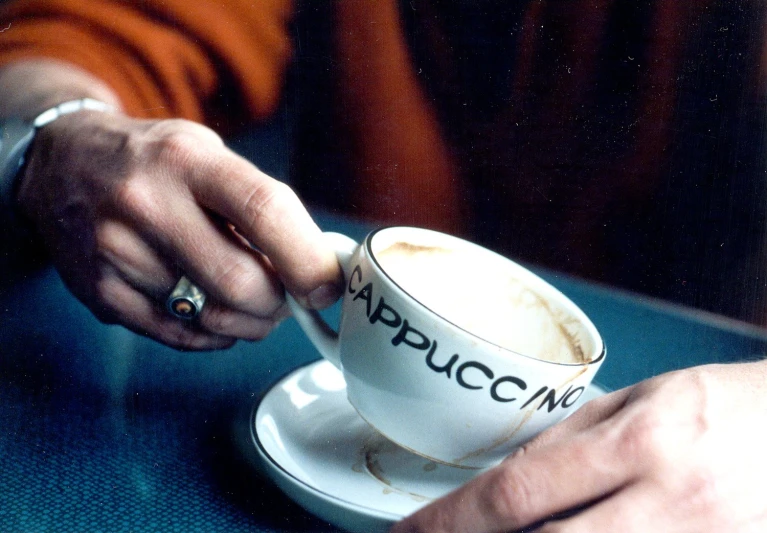 two hands grabbing coffee cup that says apuccan