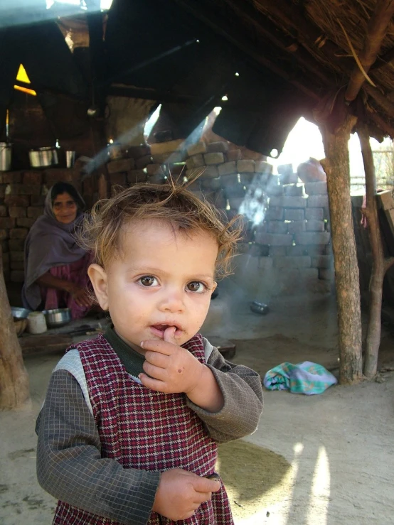 a baby girl wearing a dress outside on the dirt