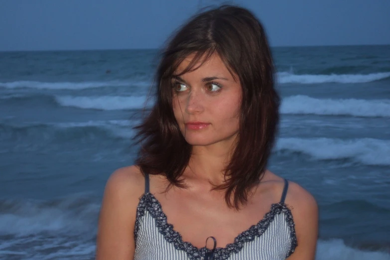 a woman in front of the ocean staring at the camera