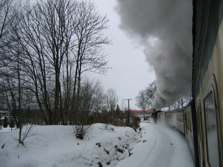 a train engine blowing smoke while traveling through the snowy country side