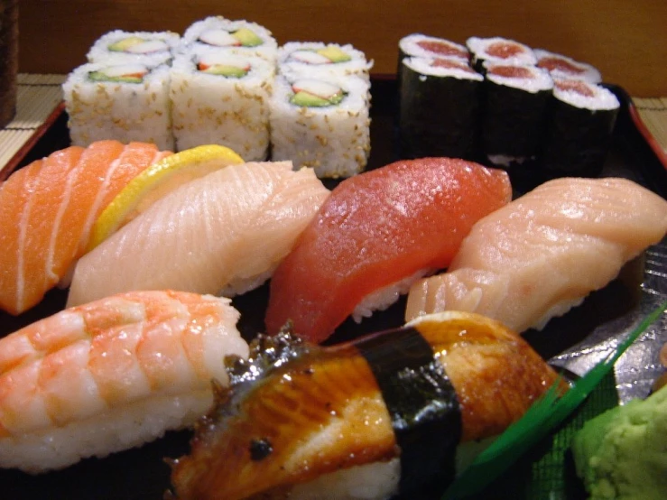 a black plate topped with assorted sushi