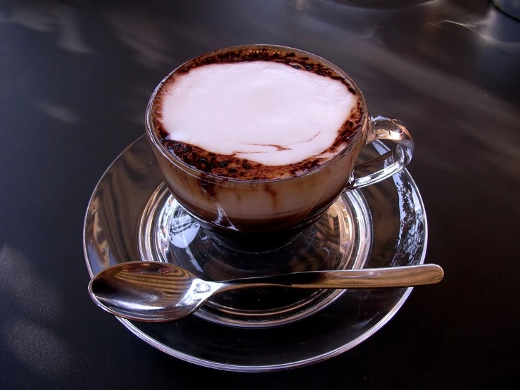 a cappuccino with whipped cream on it sits atop a glass plate