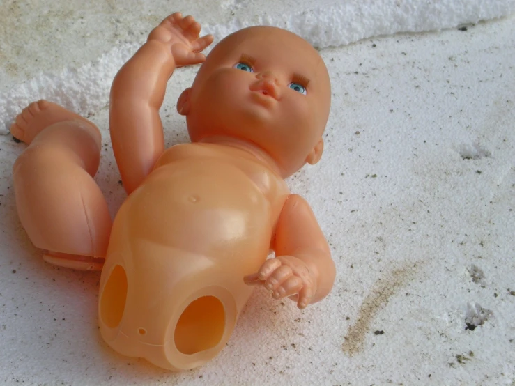a small toy sitting in the sand next to a baby doll