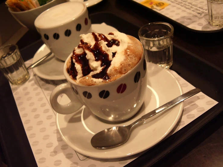 a cup of  chocolate is sitting on a plate next to two glasses