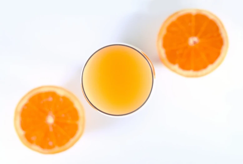 two orange halves sit next to an almost empty glass