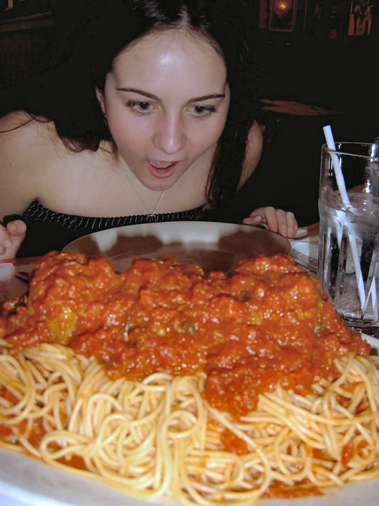 a woman sitting at a table with spaghetti and meat