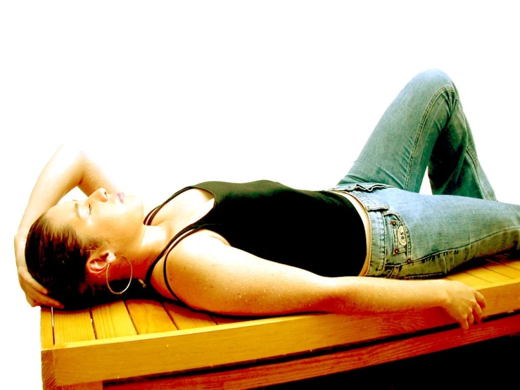 a young woman laying down on top of a wooden bench