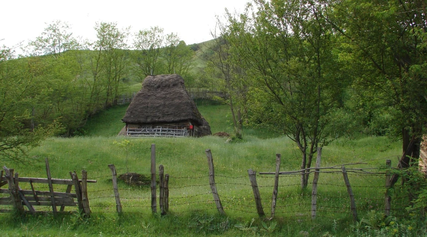 an old log house is in the middle of the field