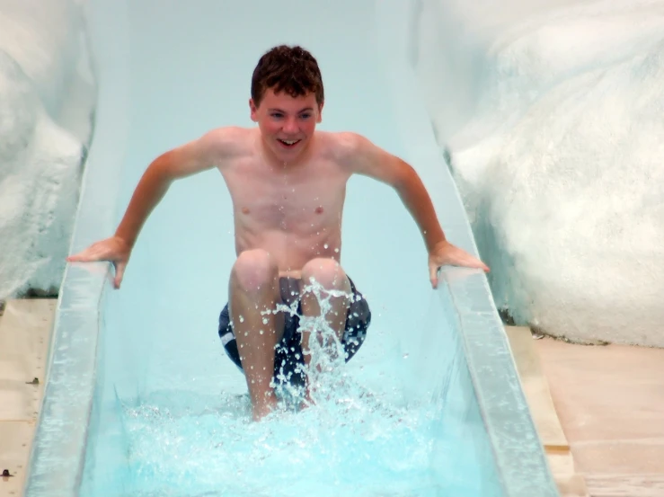 a boy slides down a water slide at a waterslide park