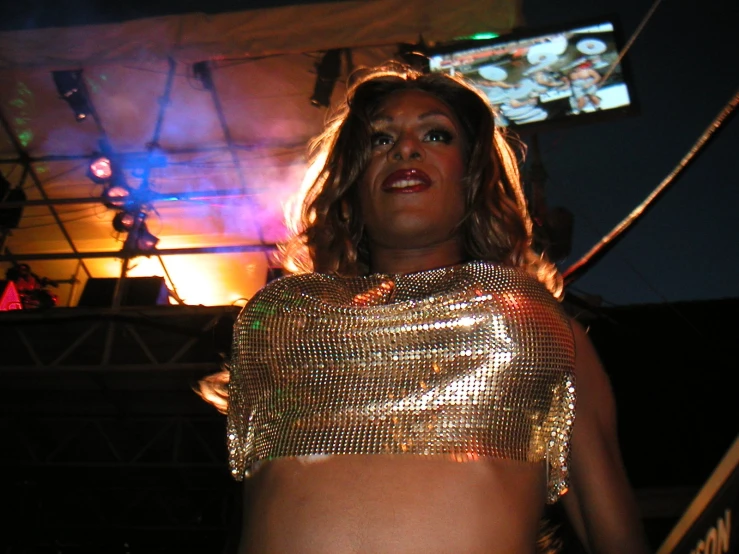 a woman in a gold outfit standing in front of stage lights