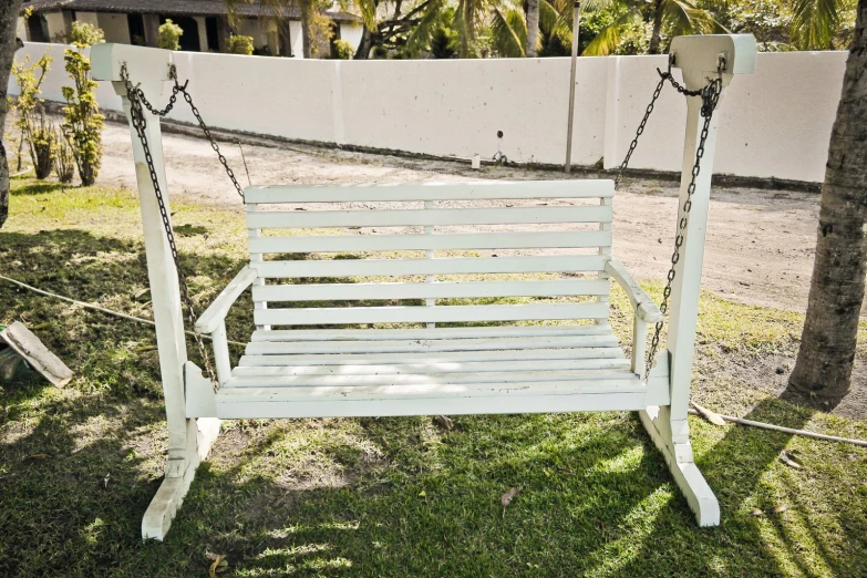 a white swing chair sitting in a grassy yard