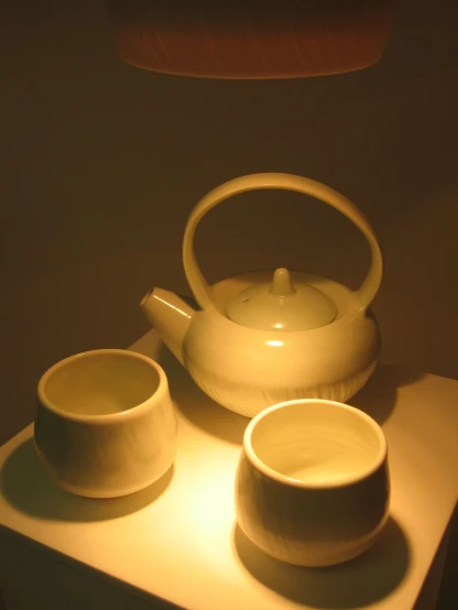 a tea pot, a tea cup and a bowl are sitting on a small shelf