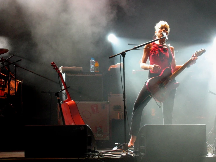 a woman in red with her guitar on stage