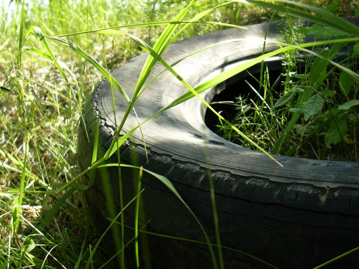 an old tire in the grass with one tire laying next to it
