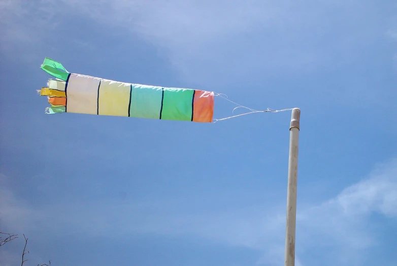 a kite flying in a blue sky above a pole