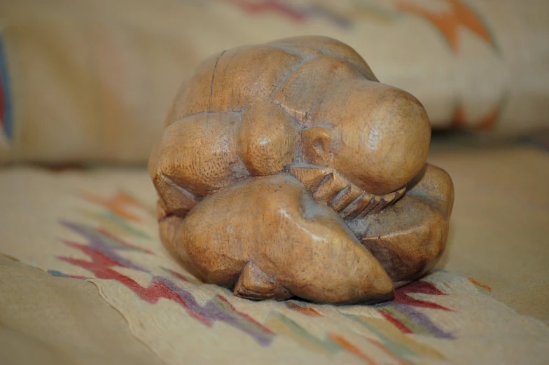 a close up of a wood statue on a pillow