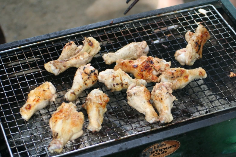 several pieces of chicken cooking on a barbecue grill