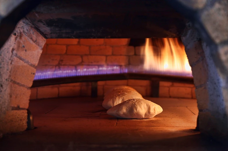 two pizzas in an oven cooking some food