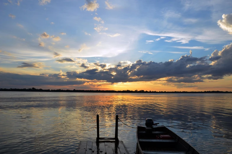 a small boat floating on top of a river at sunset