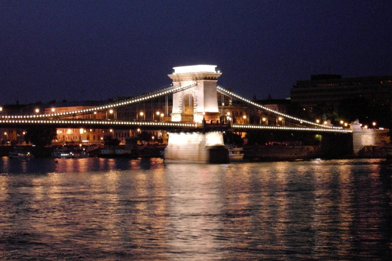 a bridge lit up at night over some water