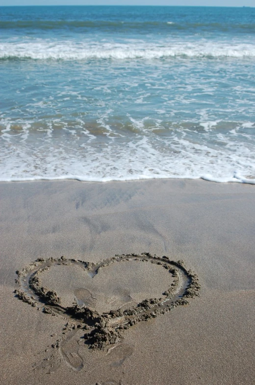 a heart shape in the sand by the ocean