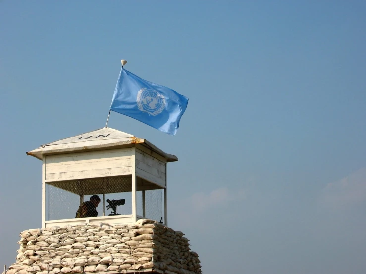 flag waving at an observation tower with stone wall and stone structure