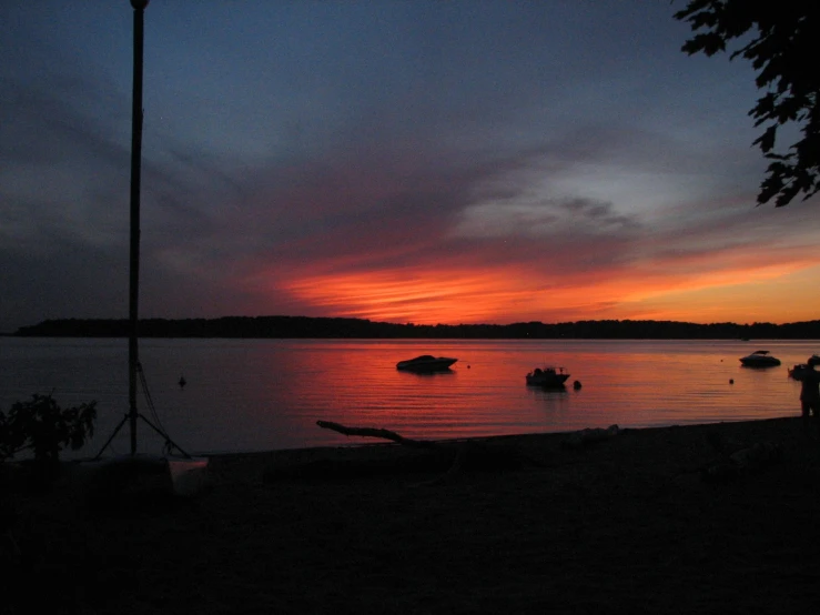 the sun is rising over the water and two small boats are in the water