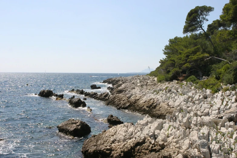 rocks are on the edge of the beach by the water