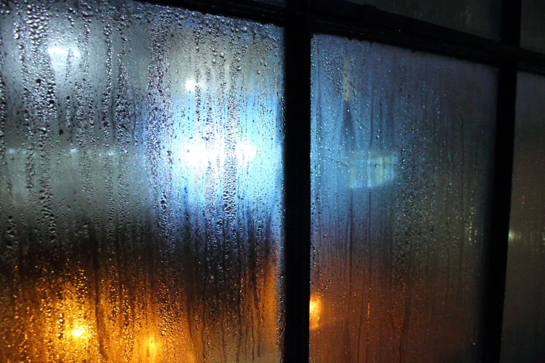 rain falls down on a window in the evening