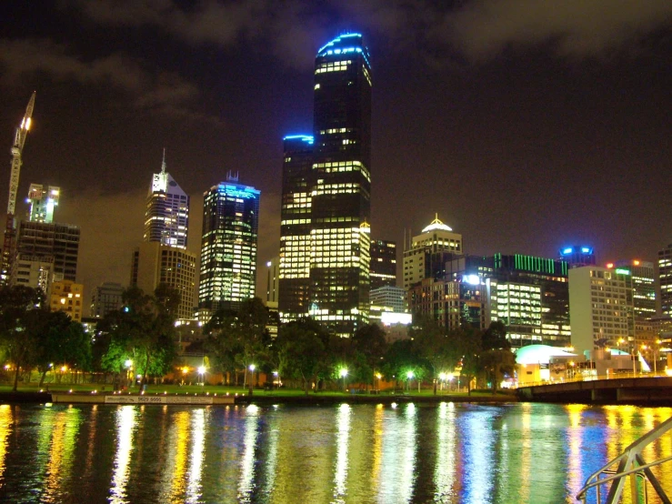 view of skyline and skyscrs at night reflected in water