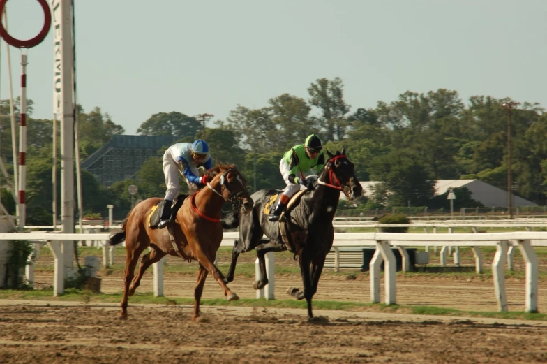 the two jockeys are riding their horses down the track