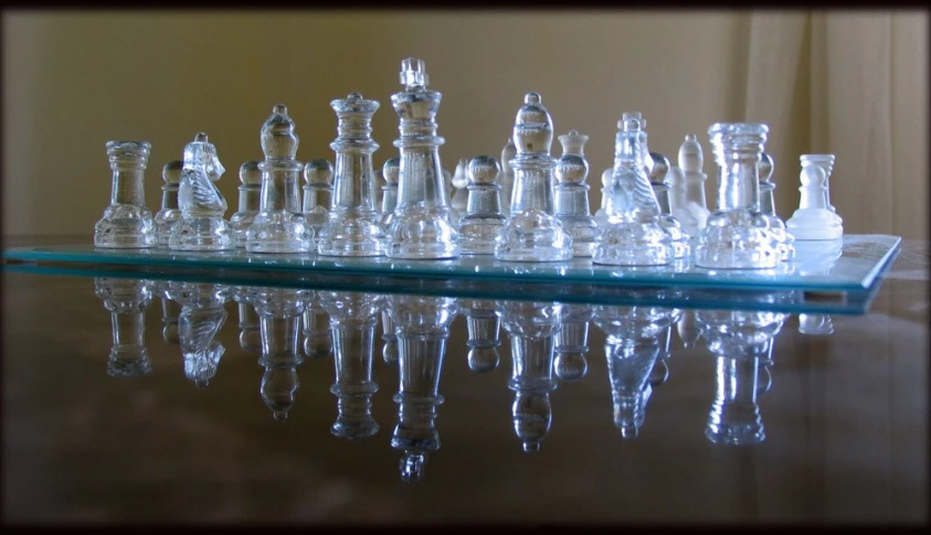 glass chess pieces are lined up on a table