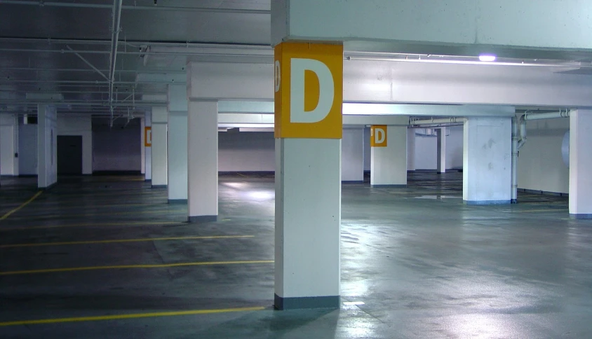 empty parking garage area with yellow and white sign