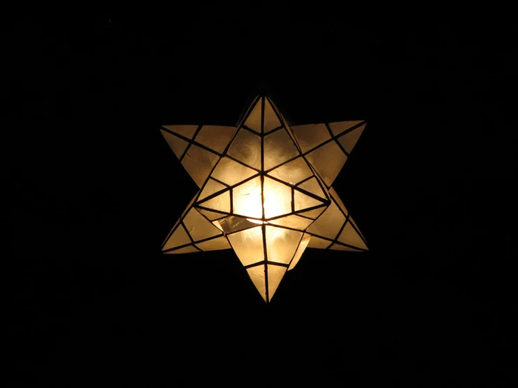 a star of david is lit up against a dark background