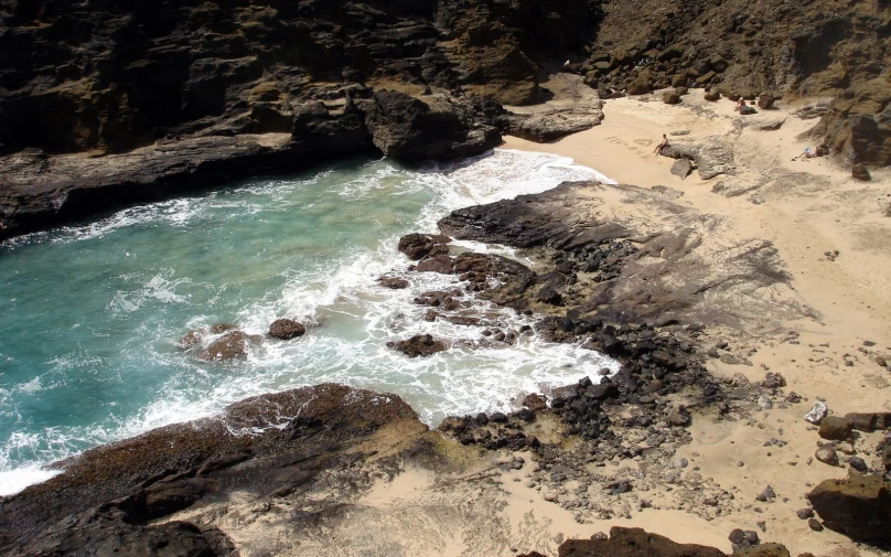 a beach with blue water surrounded by rocky cliffs