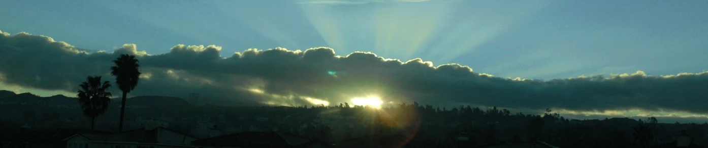 the sun peeking over the clouds and setting in an otherwise complete setting