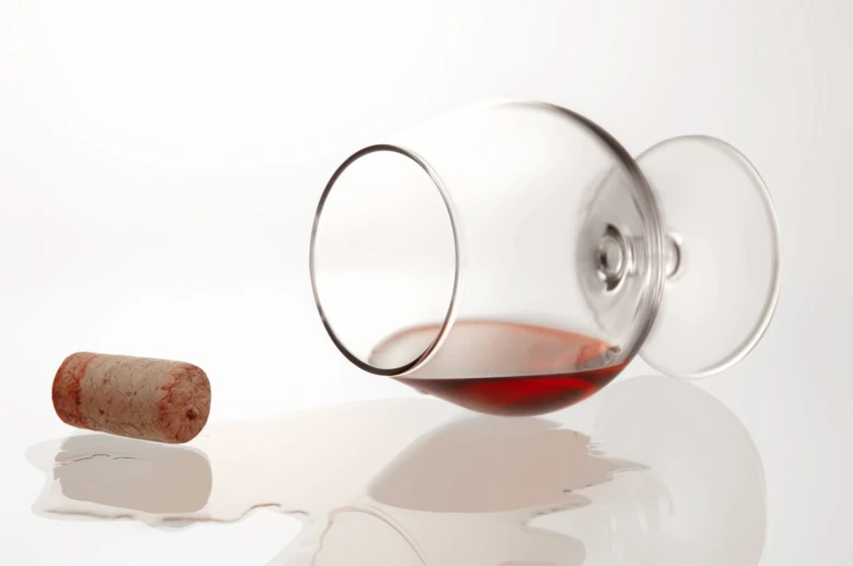 a glass that is full of wine next to a cork