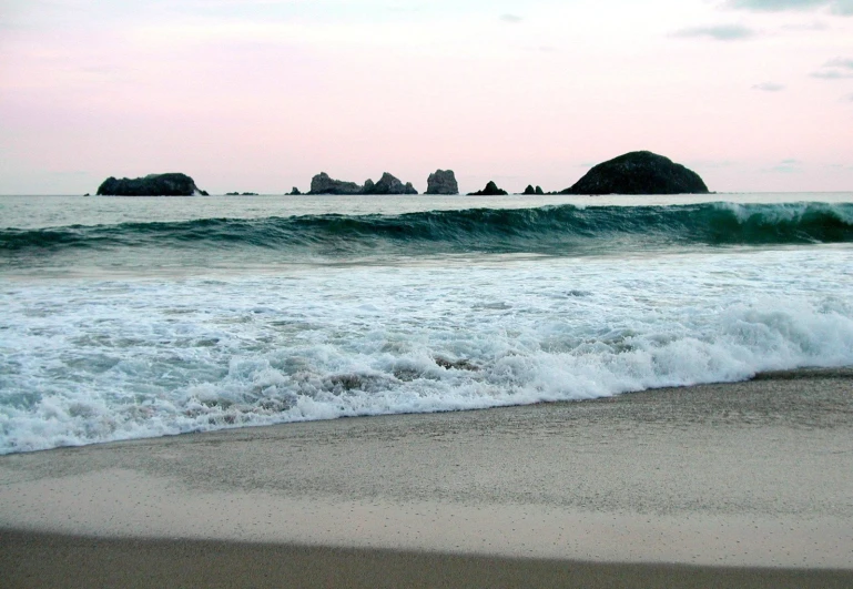 the ocean waves are hitting in front of a large rock formation