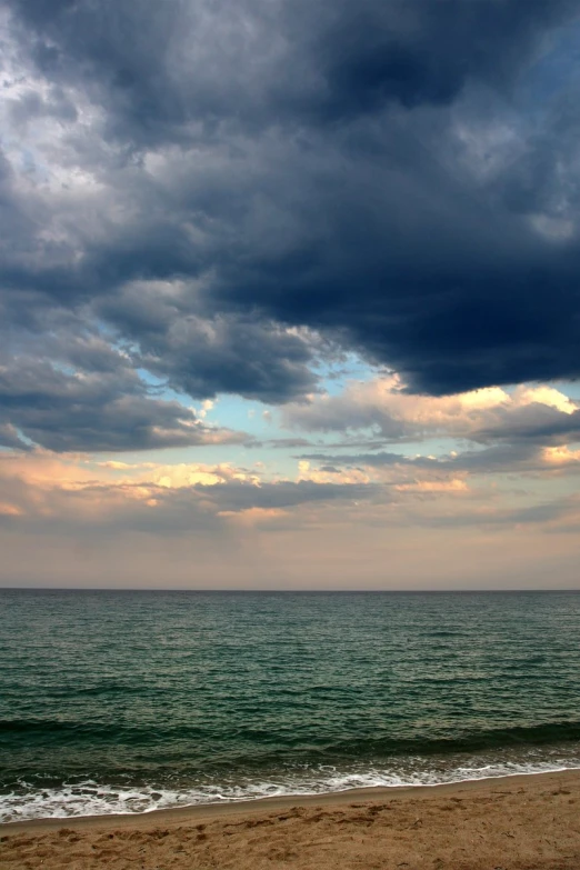 a beach with a sea on it under a cloudy sky