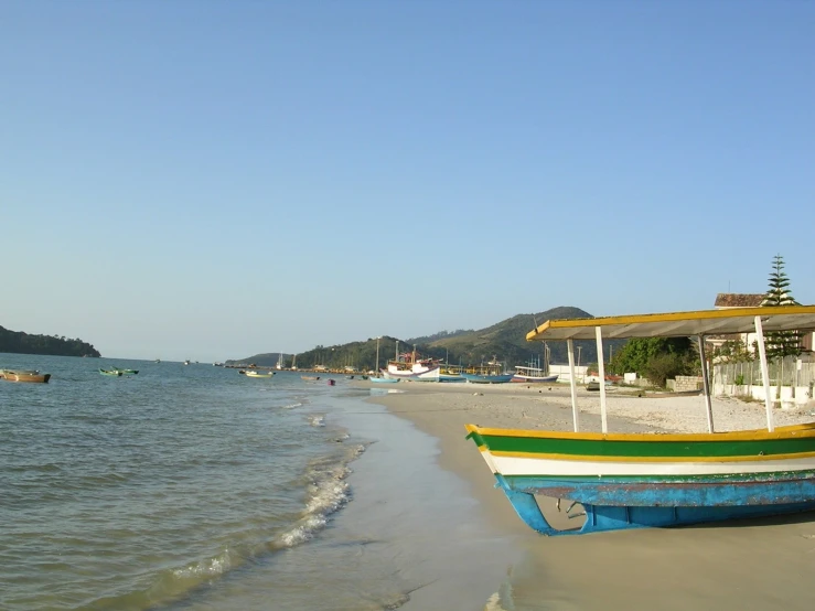 a boat is resting on the beach in front of the ocean