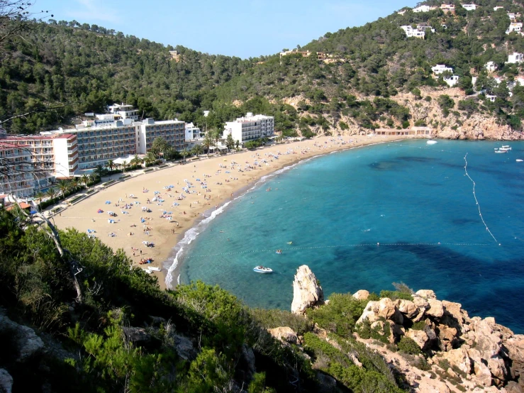 the beach in front of many resort houses with a blue sea