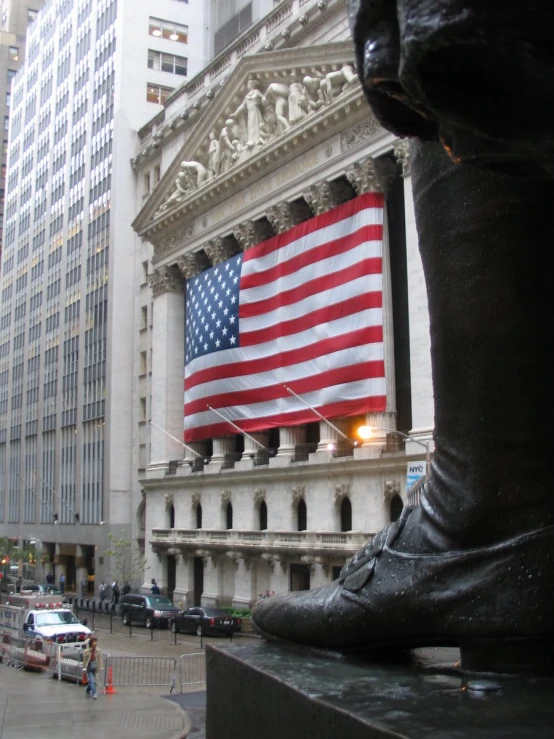 a statue is sitting next to a building with a large american flag on it