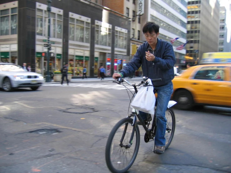 an asian male on a bike using his cell phone