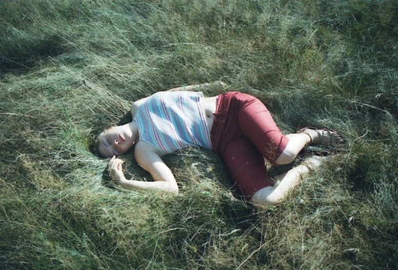 a woman laying on the grass in a field