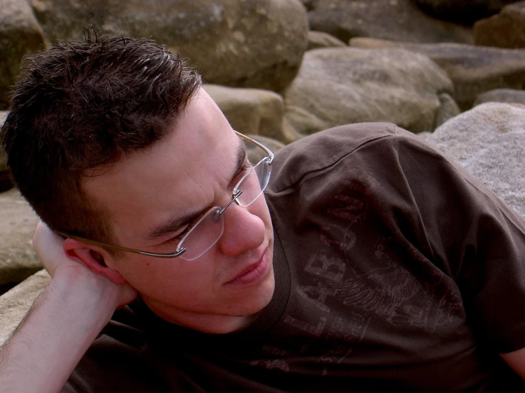 a man laying in front of a rock and water