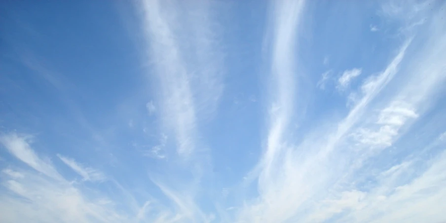 an empty beach with two large sand umbrellas and blue sky in background