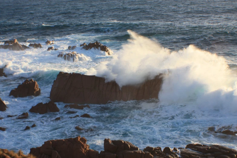 the waves crash on the rocks of a rocky shore